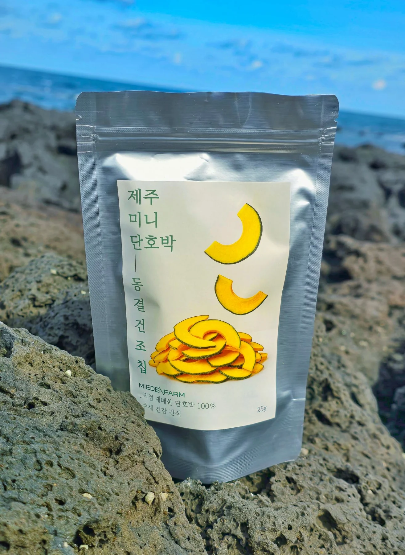 A bag of mini kabocha freeze-dried chips on basalt rock by the sea (photo by MIEDEN FARM)
