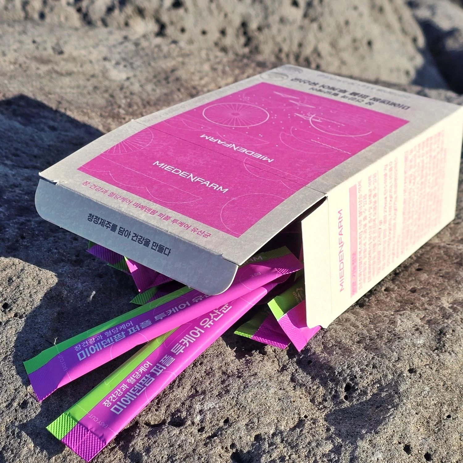 A Purple TwoCare Probiotics box and sticks on basalt rock (photo by MIEDEN FARM)